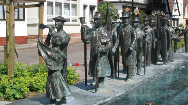 Die Bronzeplastik „Warnminner Ümgang“ stellt den jedes Jahr stattfindenden historischen Umzug in Warnemünde dar